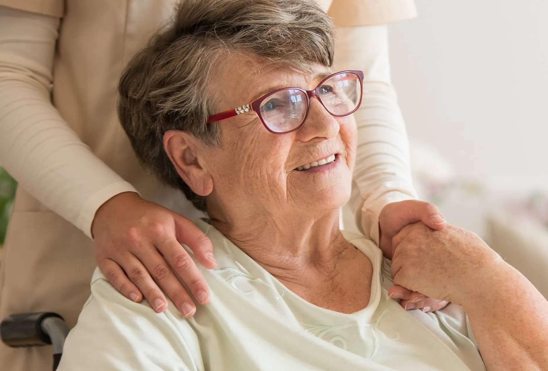 Woman happily looking off in the distance while holding an aides' hand