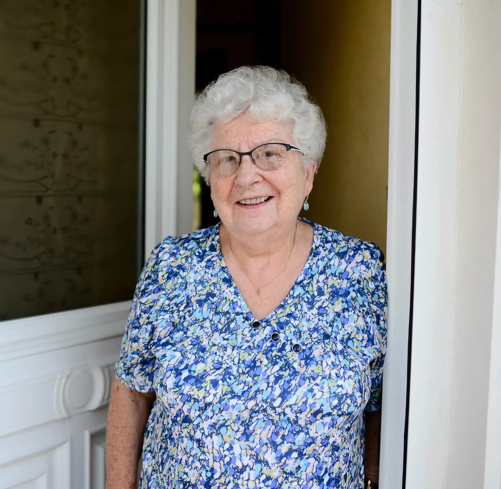 Senior woman smiling while standing in doorway