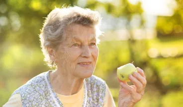elderly woman eating an apple