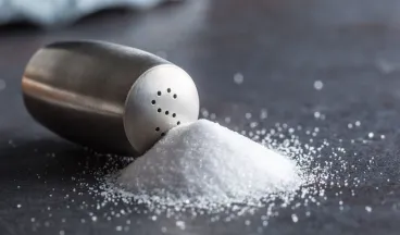 Salt shaker tipped over with a pile of salt