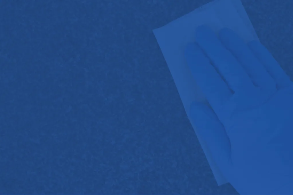 gloved hand wiping surface with paper towel