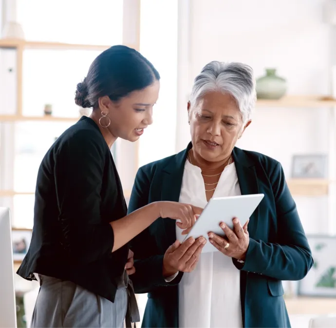 Two women looking over tablet having a conversation