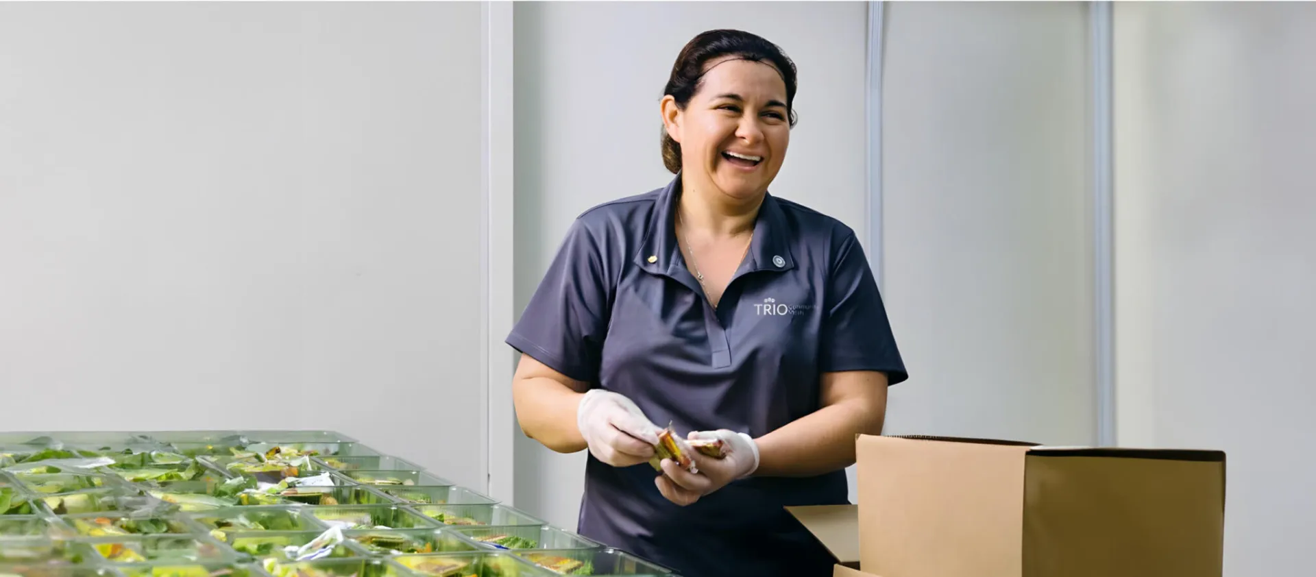 A working smiling while preparing boxed salads
