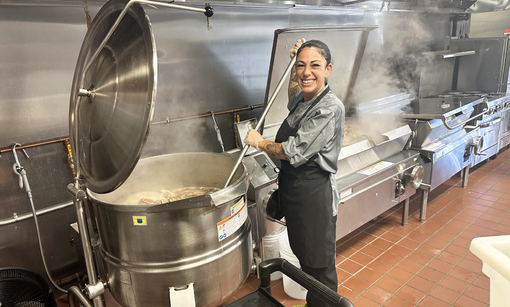 Employee smiling while stirring kettle