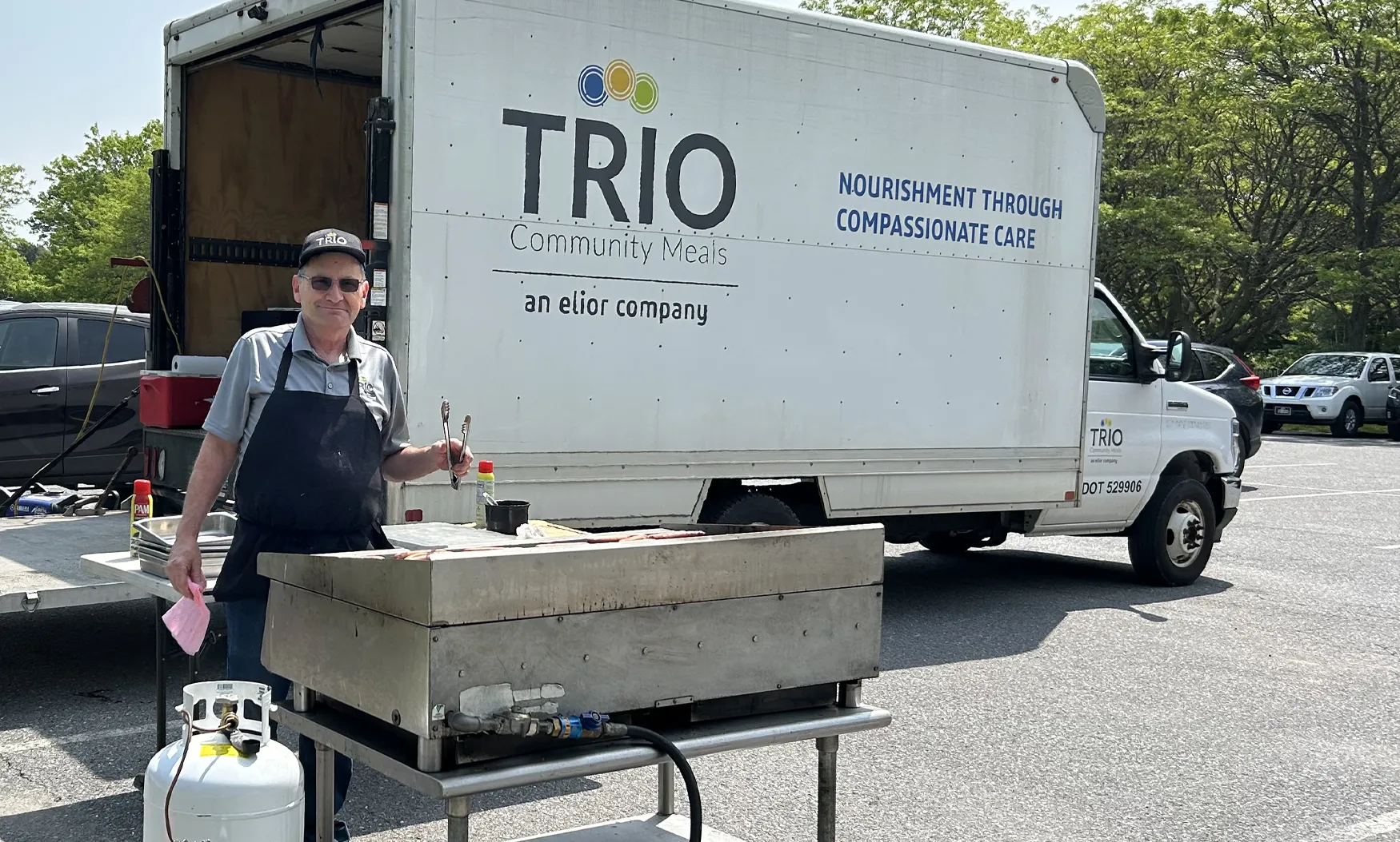 Employee cooking outdoors in front of TRIO food truck