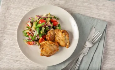 Roasted chicken thighs and vegetables on white plate