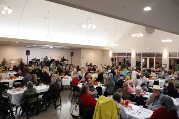 People gathered in hall having a meal together at long tables