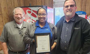 Three employees smiling in breakrom