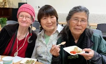 three smiling women trying food samples