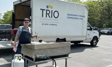 Employee cooking outdoors in front of TRIO food truck