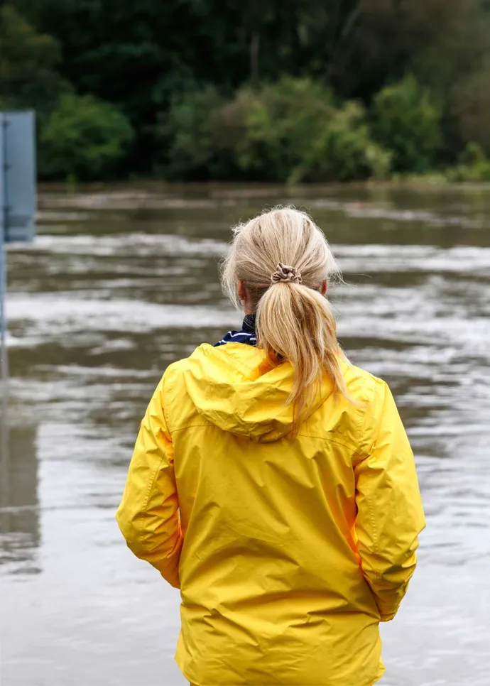 Woman in yellow raincoat overlooking flooded area