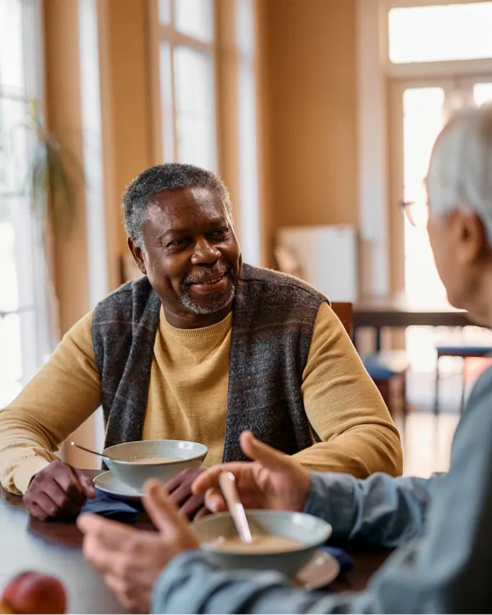 Two senior males having breakfast at table